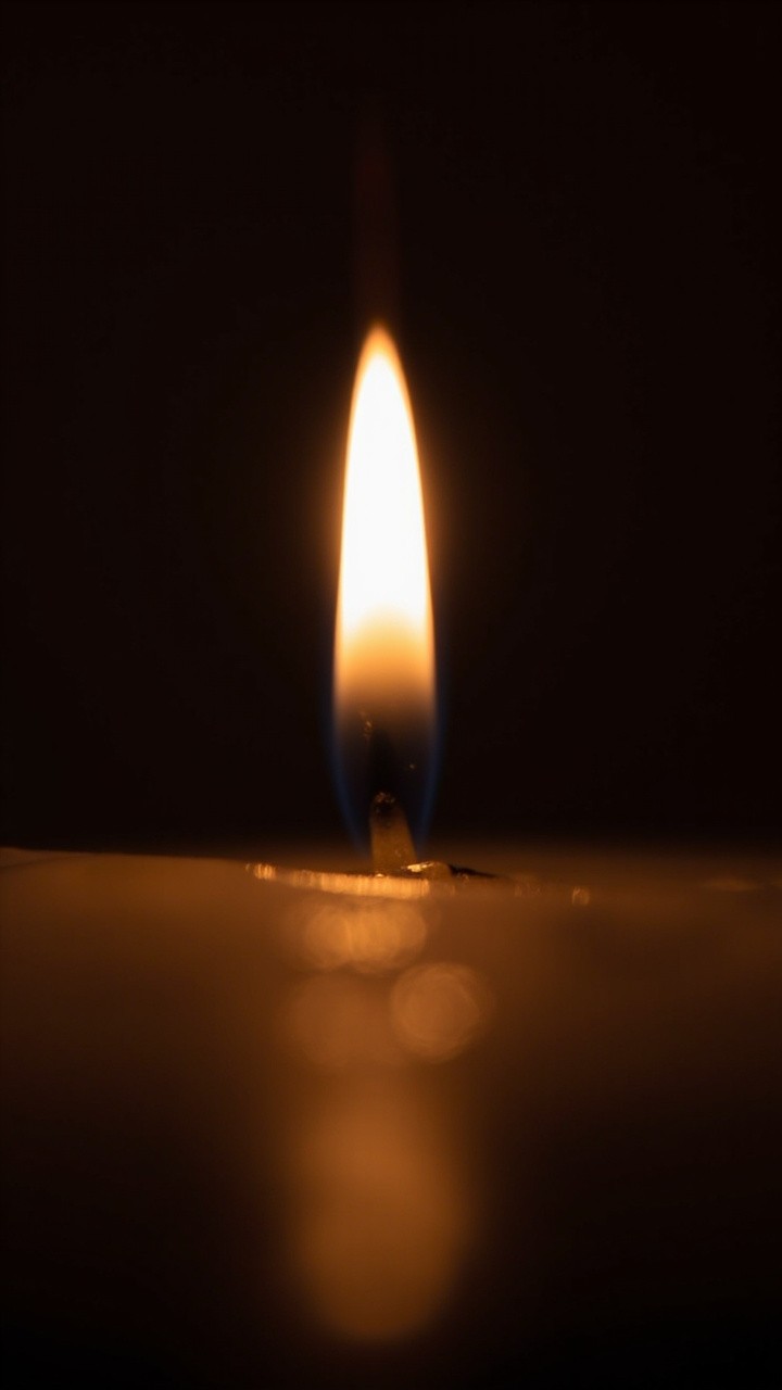 A Small Candle Burnishing Golden Glow in Dim Room