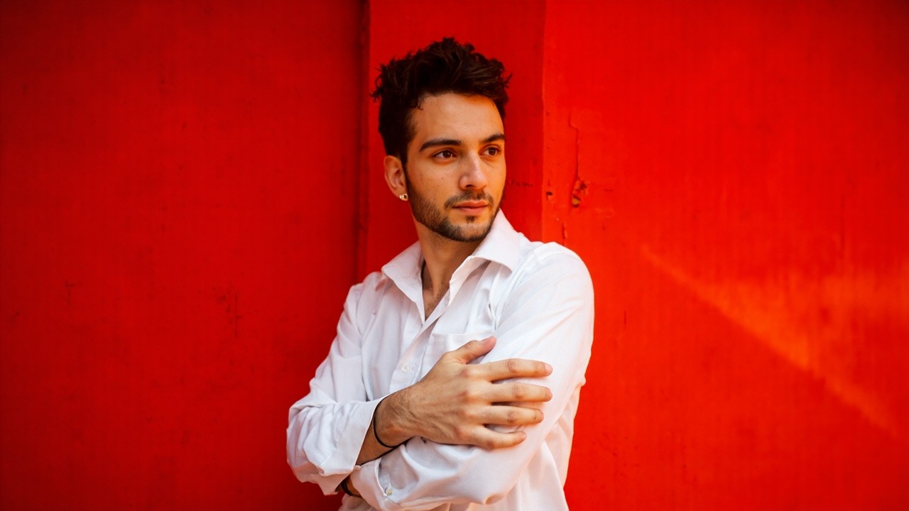 Confident Man in White Shirt Against Red Wall