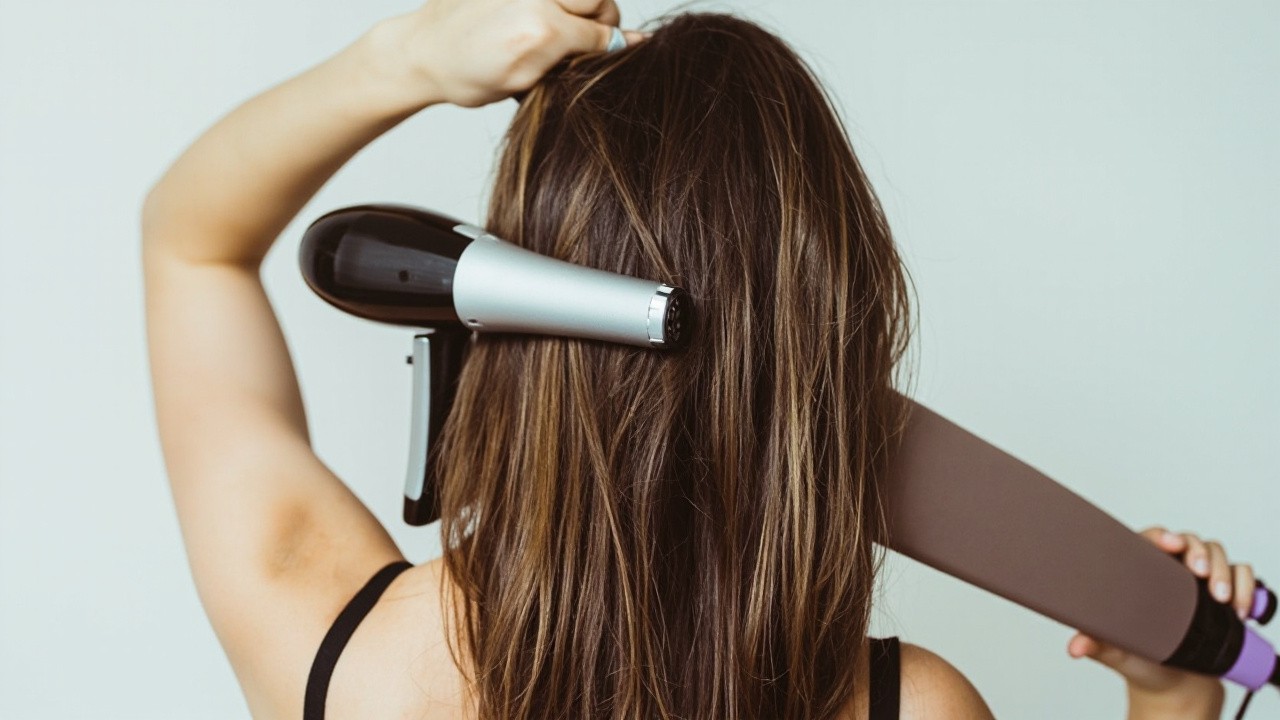 Girl Holding Hairdryer and Straightener, View from Behind