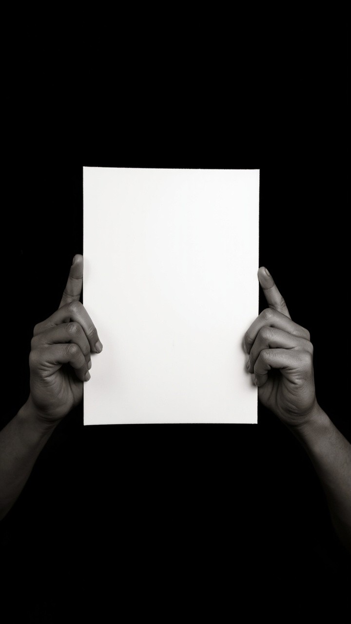 Holding Blank Paper Against Solid Black Background